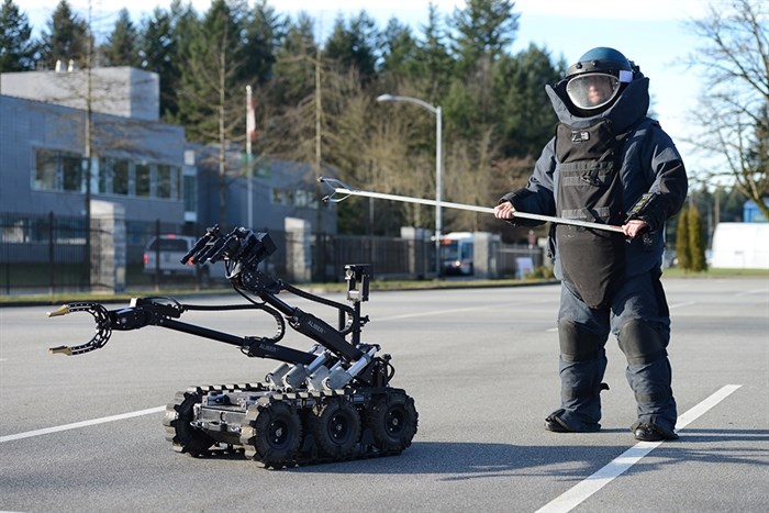RCMP in a bomb suit with a robot beside him.