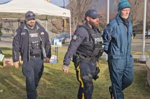 A man in handcuffs is escorted by a police officer.
