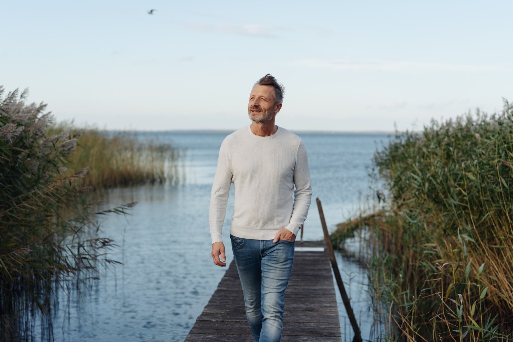 The De Pieri Clinic And The role of Testosterone Therapy in Longevity and Quality of Life | iNFOnews.ca Man in a sweater walking along a wooden dock by a lake.