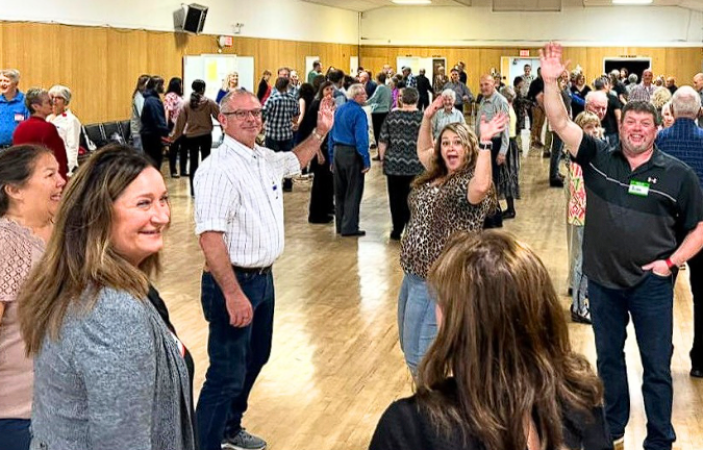 A crowd of dancers seen in a community hall.