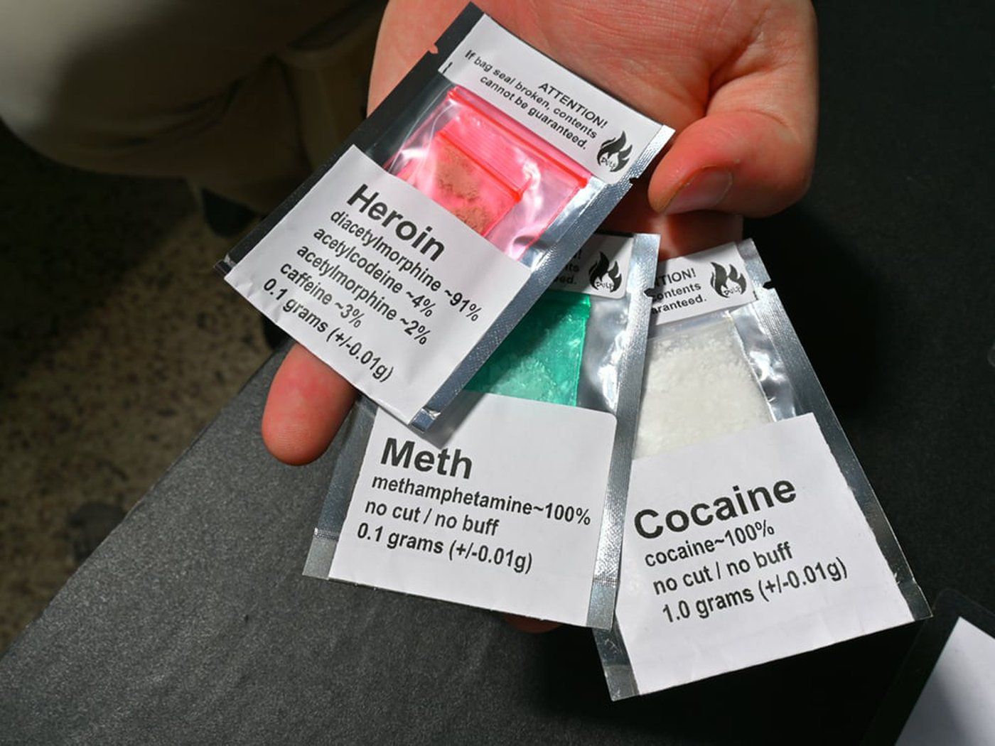 A person holds small packets of heroin, meth and cocaine.