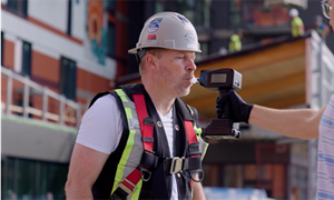 A construction worker blowing into a breathalyzer.