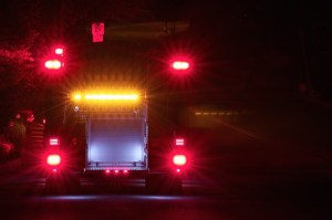 The rear of a fire truck with emergency lights on at night.