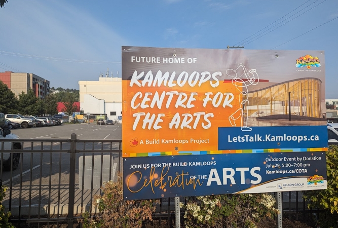 A billboard advertises an arts venue with a parking lot in the background