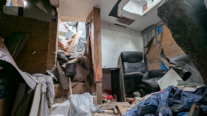A room with a skylight, an office chair and scattered garbage
