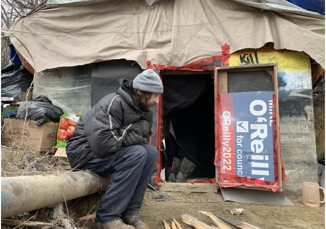 Man sitting in front of a makeshift shelter