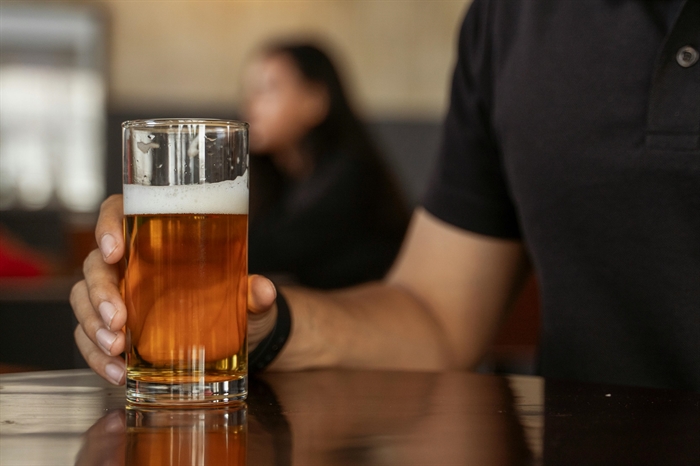 A man hold a beer at a bar.