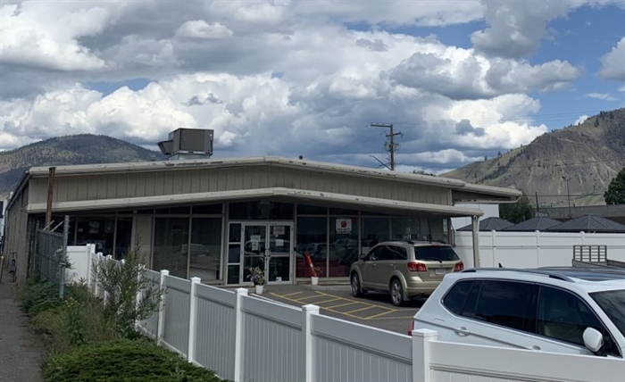 A storefront and parking lot with mountains in background.