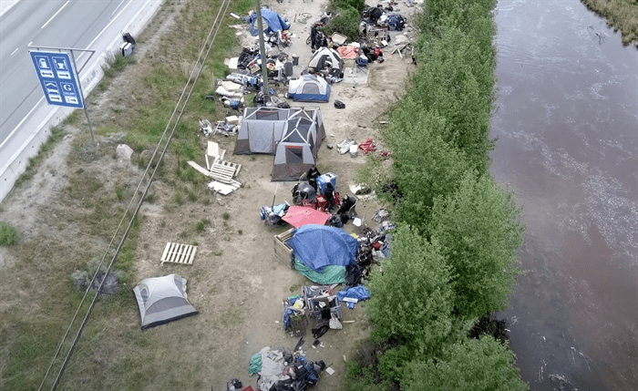 An aerial view of a homeless encampment with tents and debris.