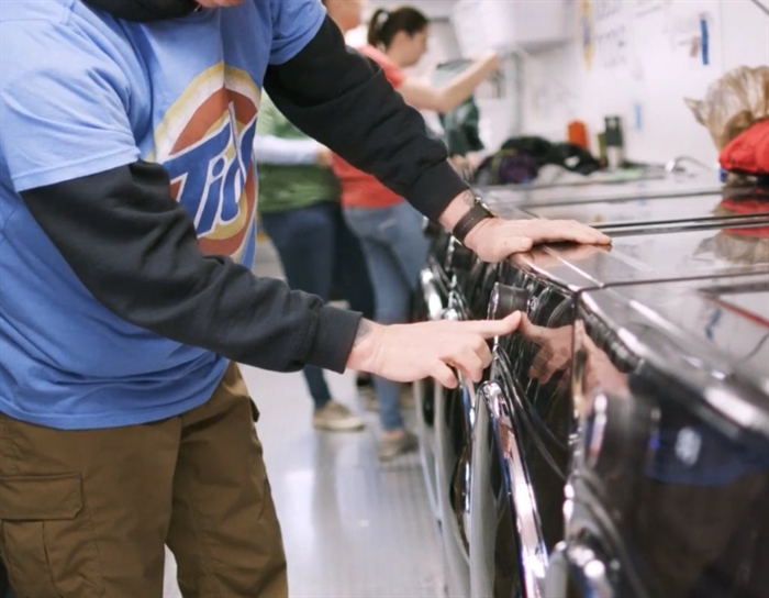 Man stands at washing machine with Tide shirt on