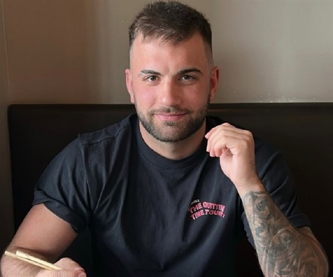 A man wearing a black T-shirt poses for a photo.