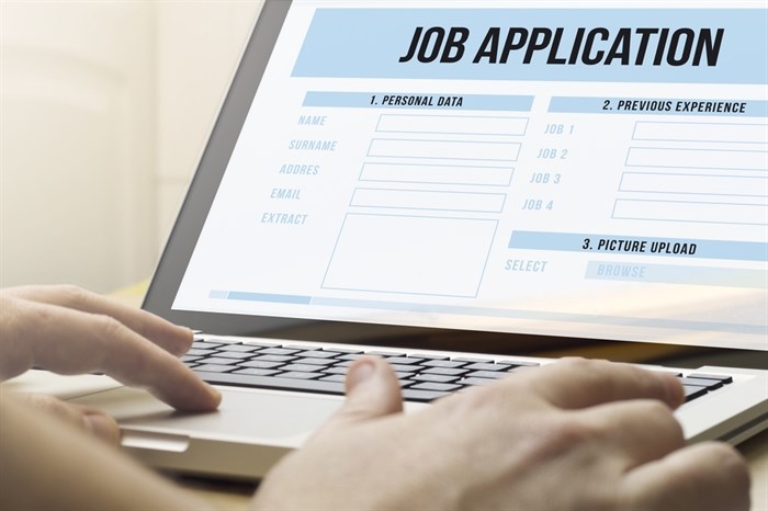 A close up of someone typing on a laptop filling out a job application.