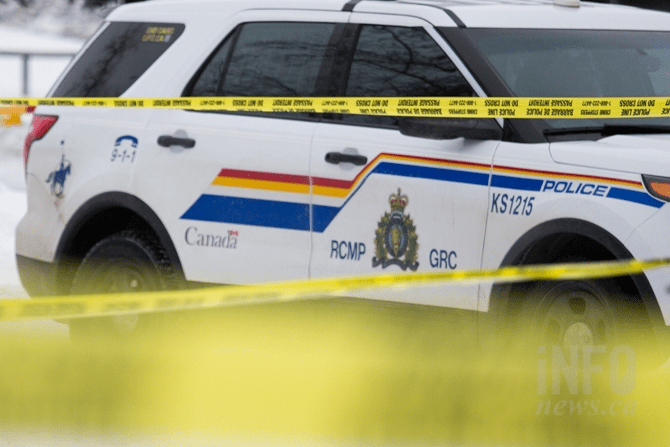 An RCMP vehicle is seen behind yellow police tape.