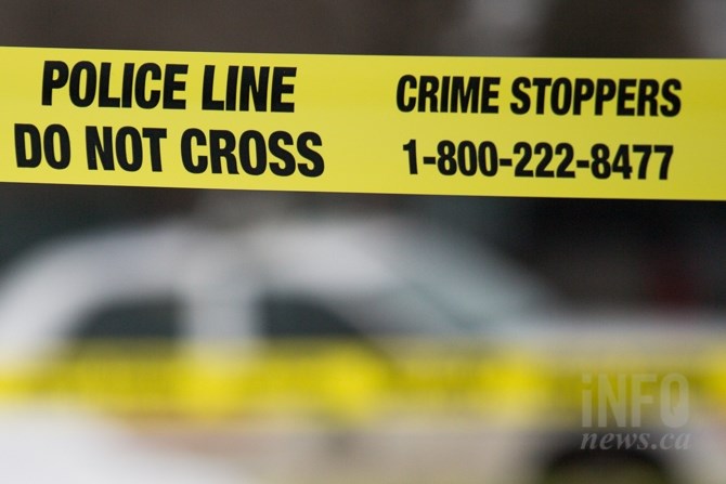 Yellow police tape is seen at a crime scene with a police car in the background.