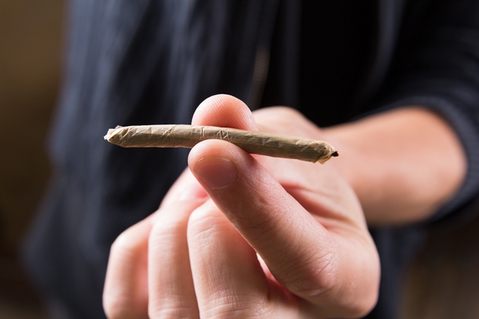 Someone holding poorly rolled joint.