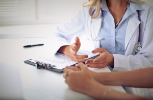 A doctor speaks with a patient in a clinical setting.