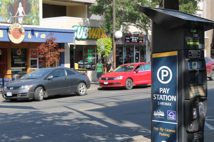 A downtown street with an electronic parking metre in the foreground.