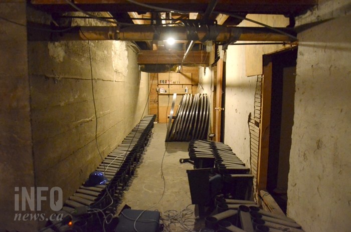 Giant old film reels appear in a dimly lit, unfinished hallway.