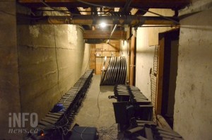Giant old film reels appear in a dimly lit, unfinished hallway.