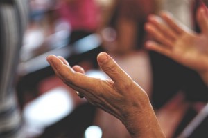 Praying hands in the air, palms up.