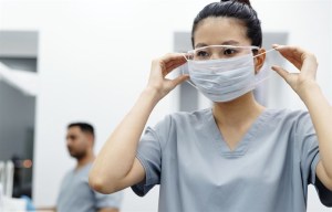 A health-care worker putting on a mask.