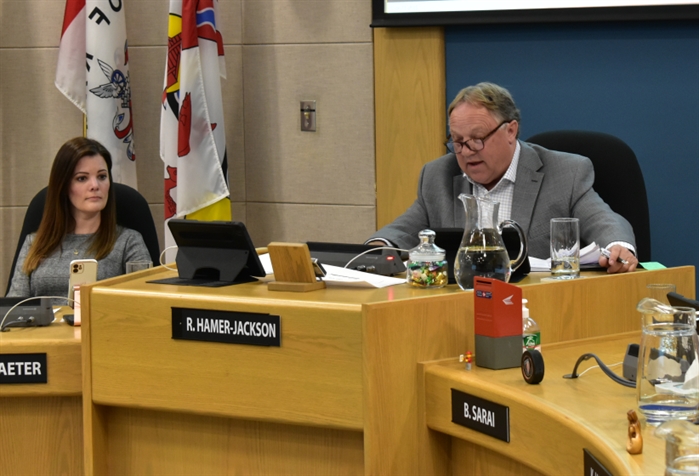 A man and a woman in city council chambers.