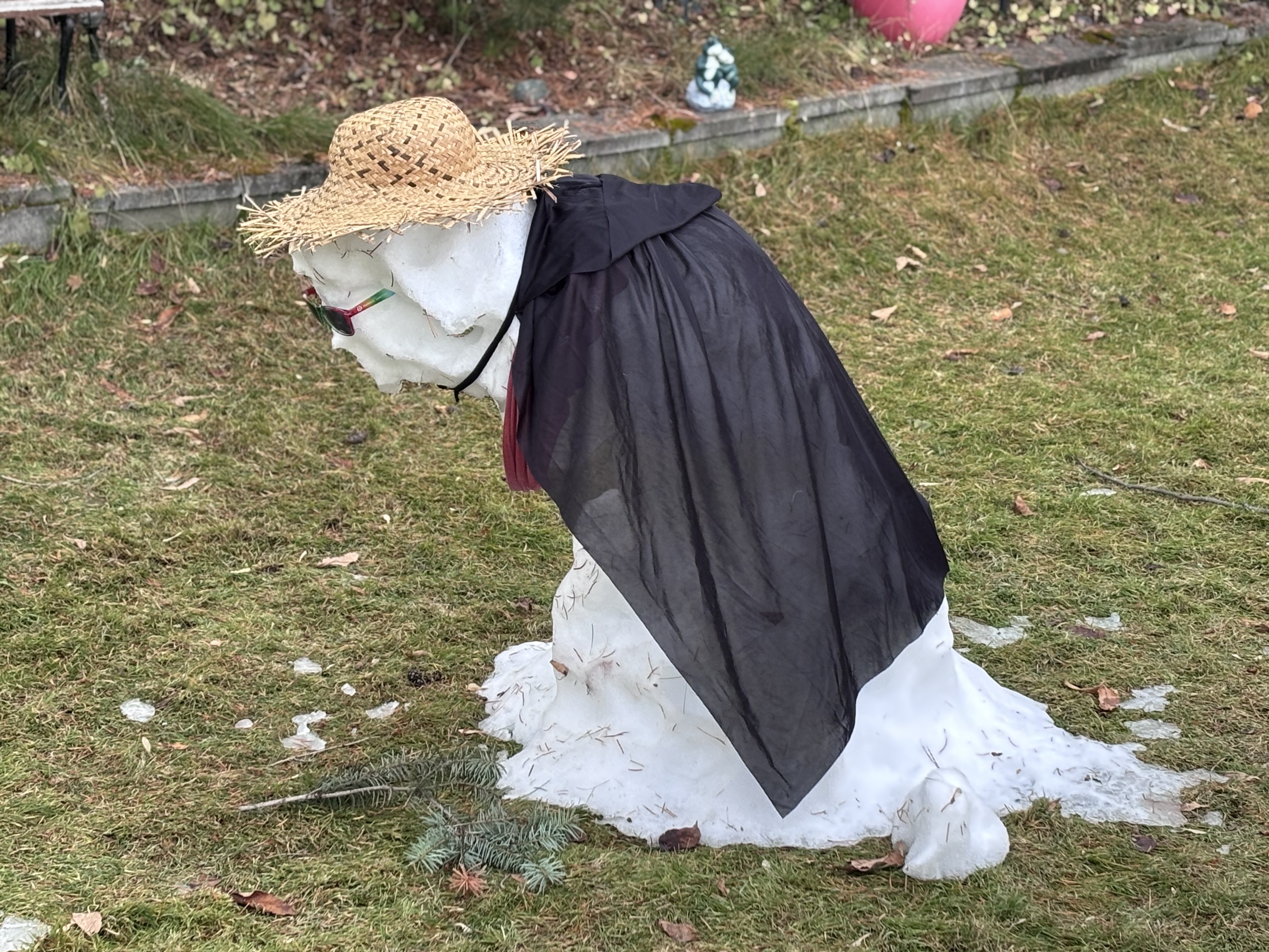 A melting snowman is dressed like an old lady.
