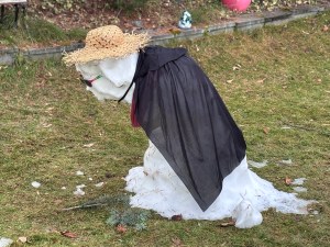 A melting snowman is dressed like an old lady.