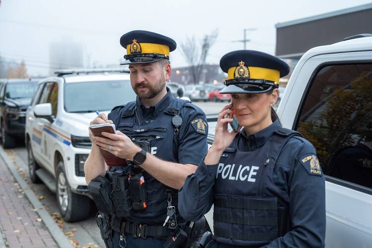 Two RCMP officers pose for a photo wearing their new regulation navy blue uniform shirts.