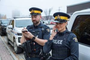 Two RCMP officers pose for a photo wearing their new regulation navy blue uniform shirts.