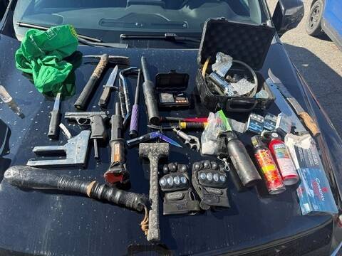 A collection of illegal weapons on the hood of a vehicle.