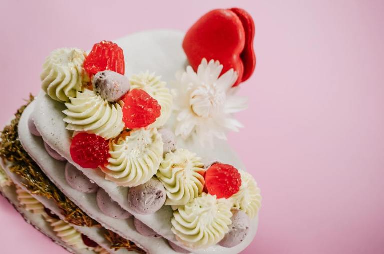 A heart shaped macaron is decorated with candies.