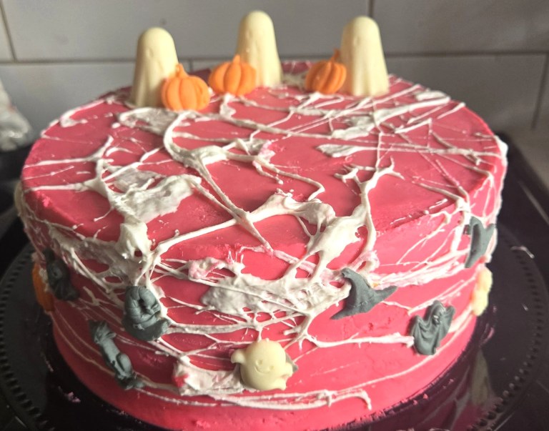 A pink cake has a Halloween theme.