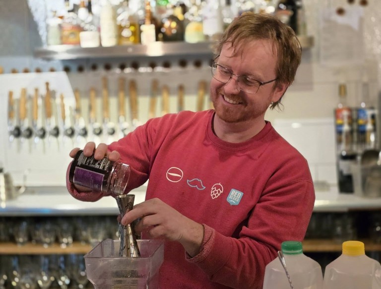 A man in a red shirt mixes a cocktail.
