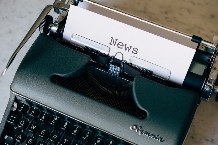 A typewrite with the word news typed onto a piece of white paper.