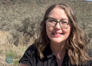 A young woman with glasses smiles at the camera.