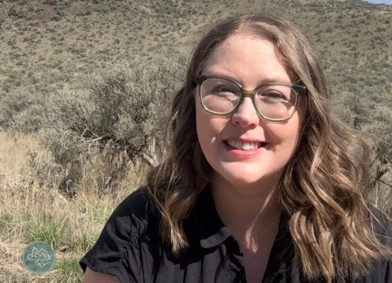 A young woman with glasses smiles at the camera.