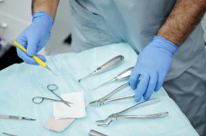 A doctor wearing gloves selects a medical surgery instrument.