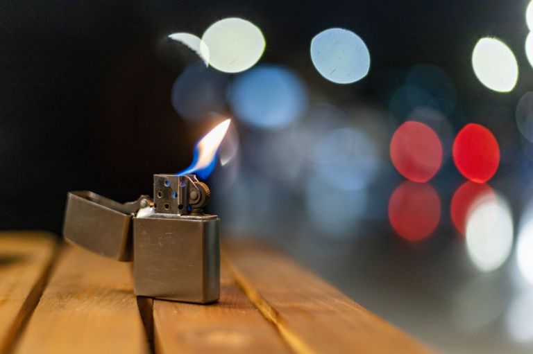 A lit cigarette lighter on a table at night.
