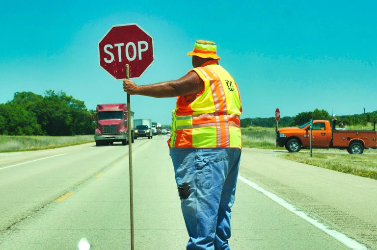 A man stand in the road with a stop sign.
