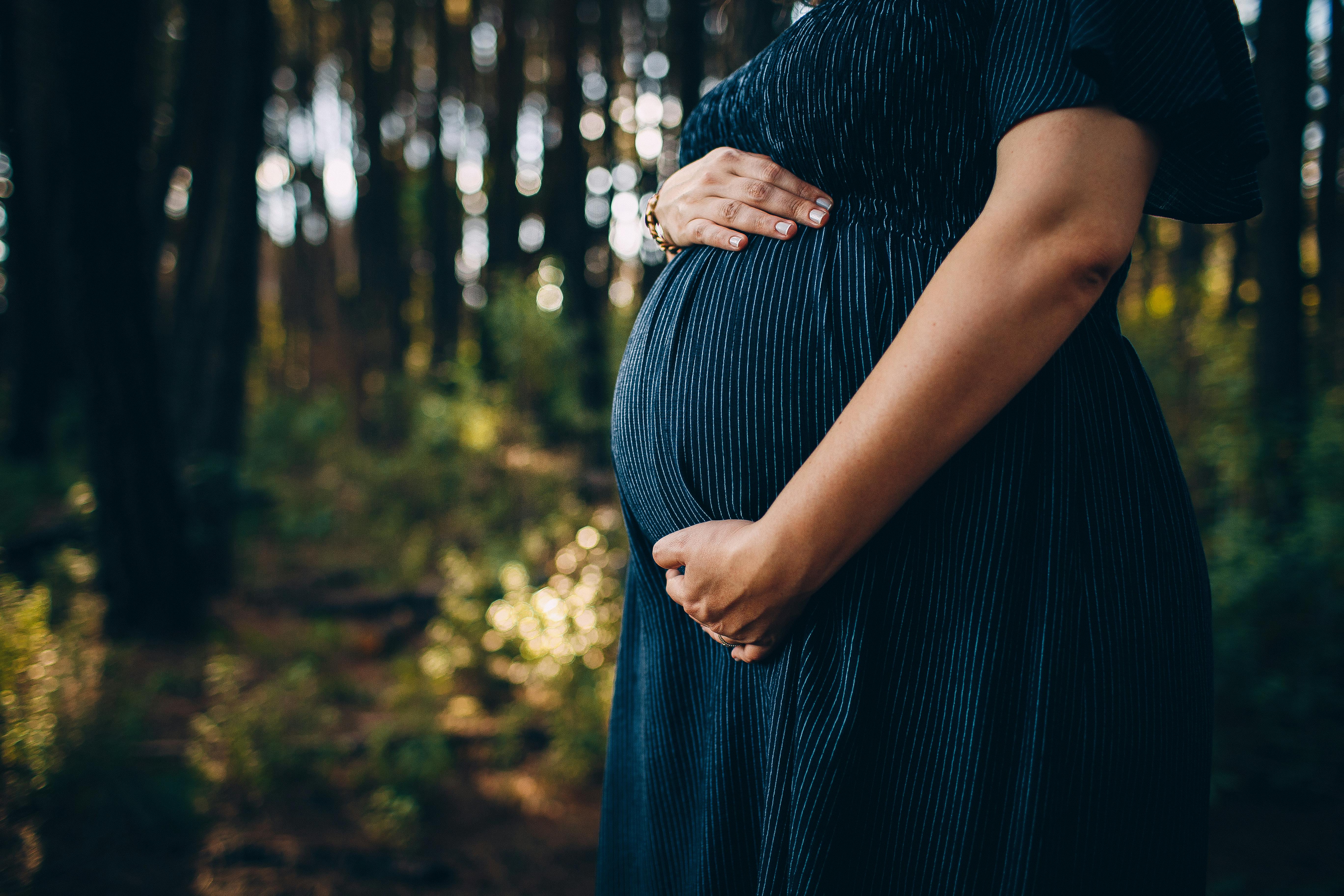 A pregnant woman holds her belly.
