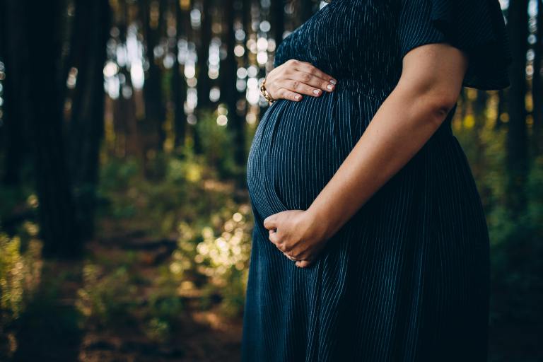 A pregnant woman holds her belly.