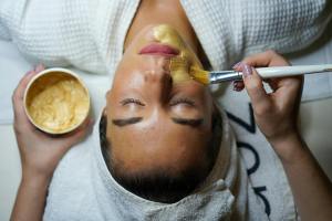 A person applies a beauty product to a woman's face during a spa treatment.