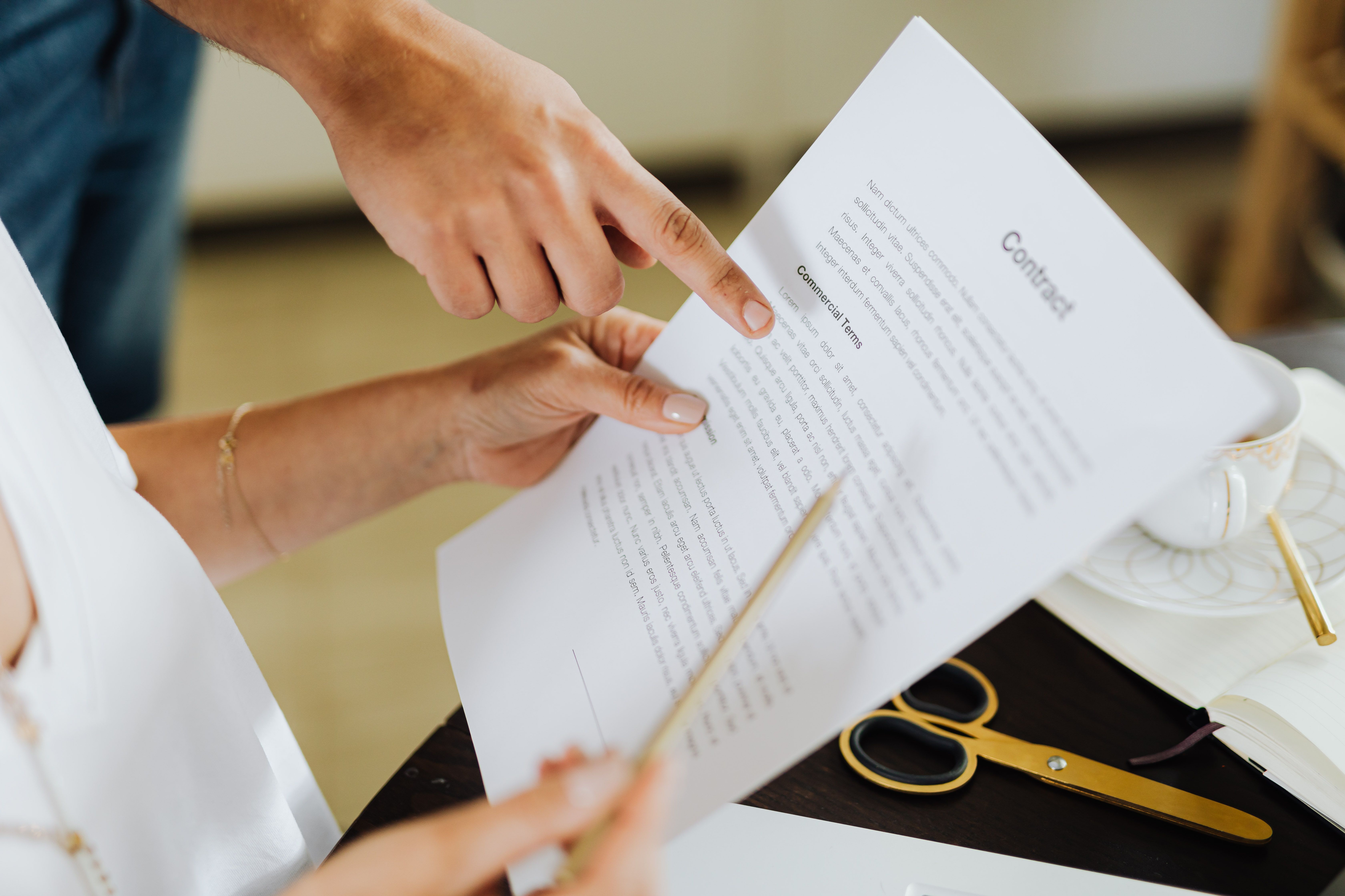 a person holds a peice of paper and a pen before signing a contract