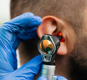 A person uses a handheld device to look into somebody's ear.