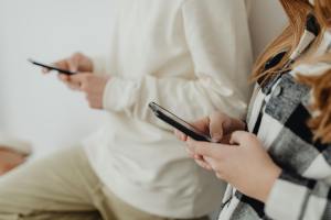Two people stare down at their cell phones.