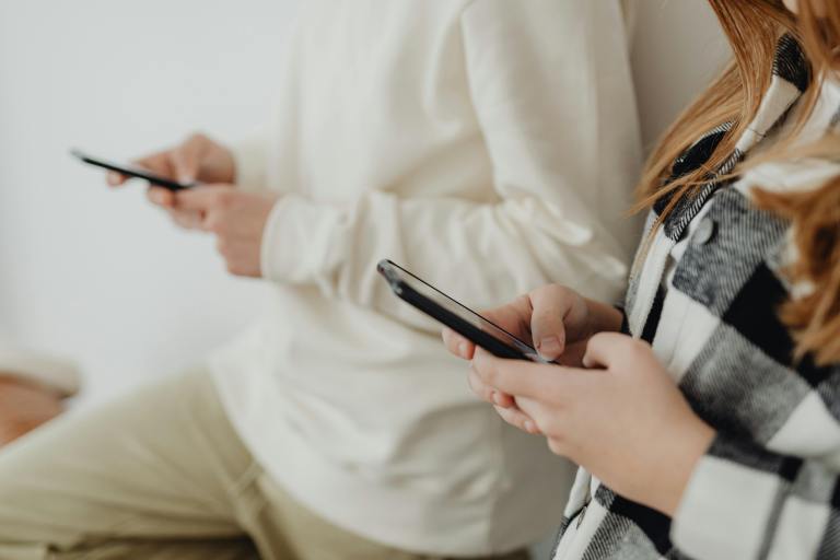 Two people stare down at their cell phones.
