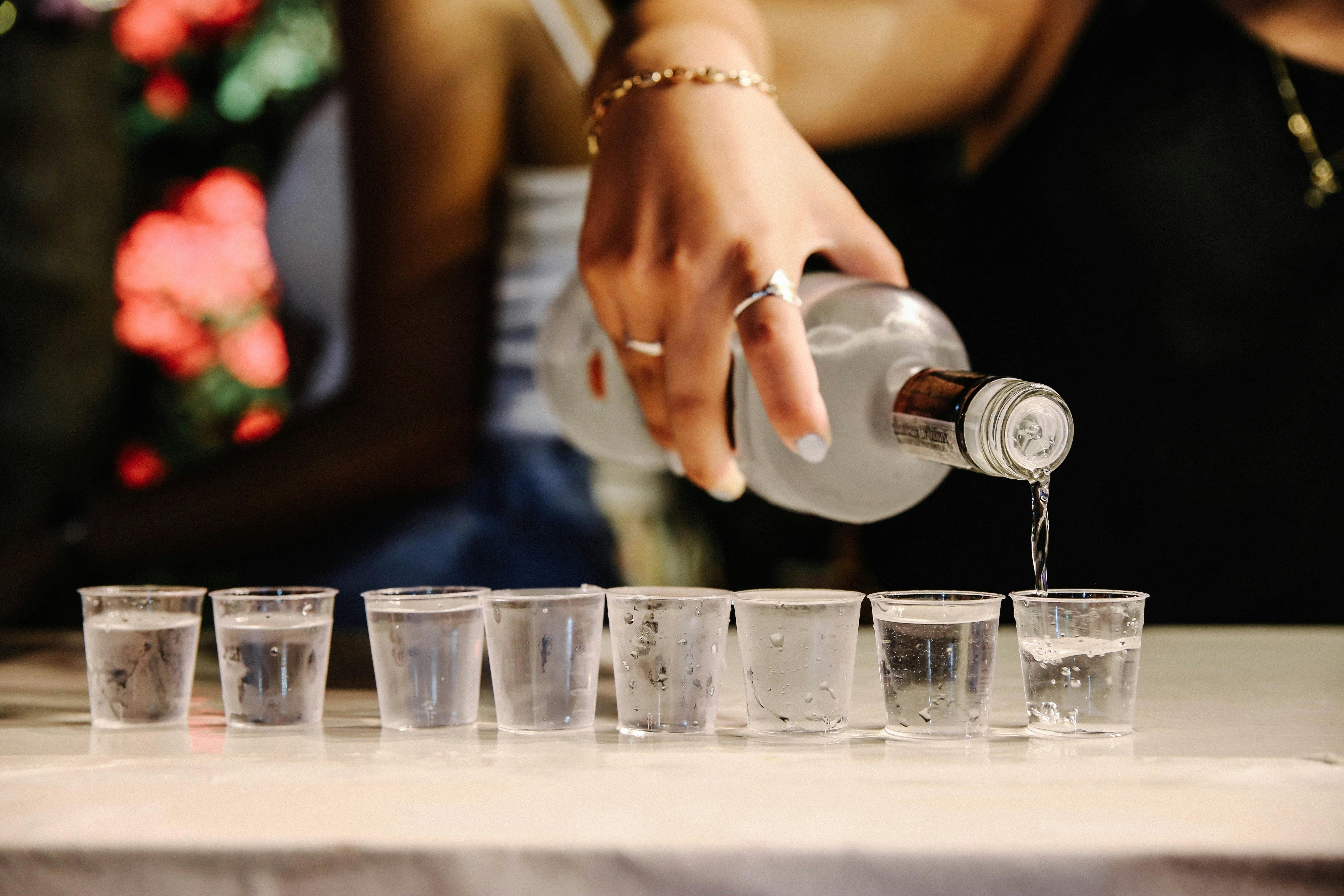 A bottle of liquor is pourced into a shot glass.