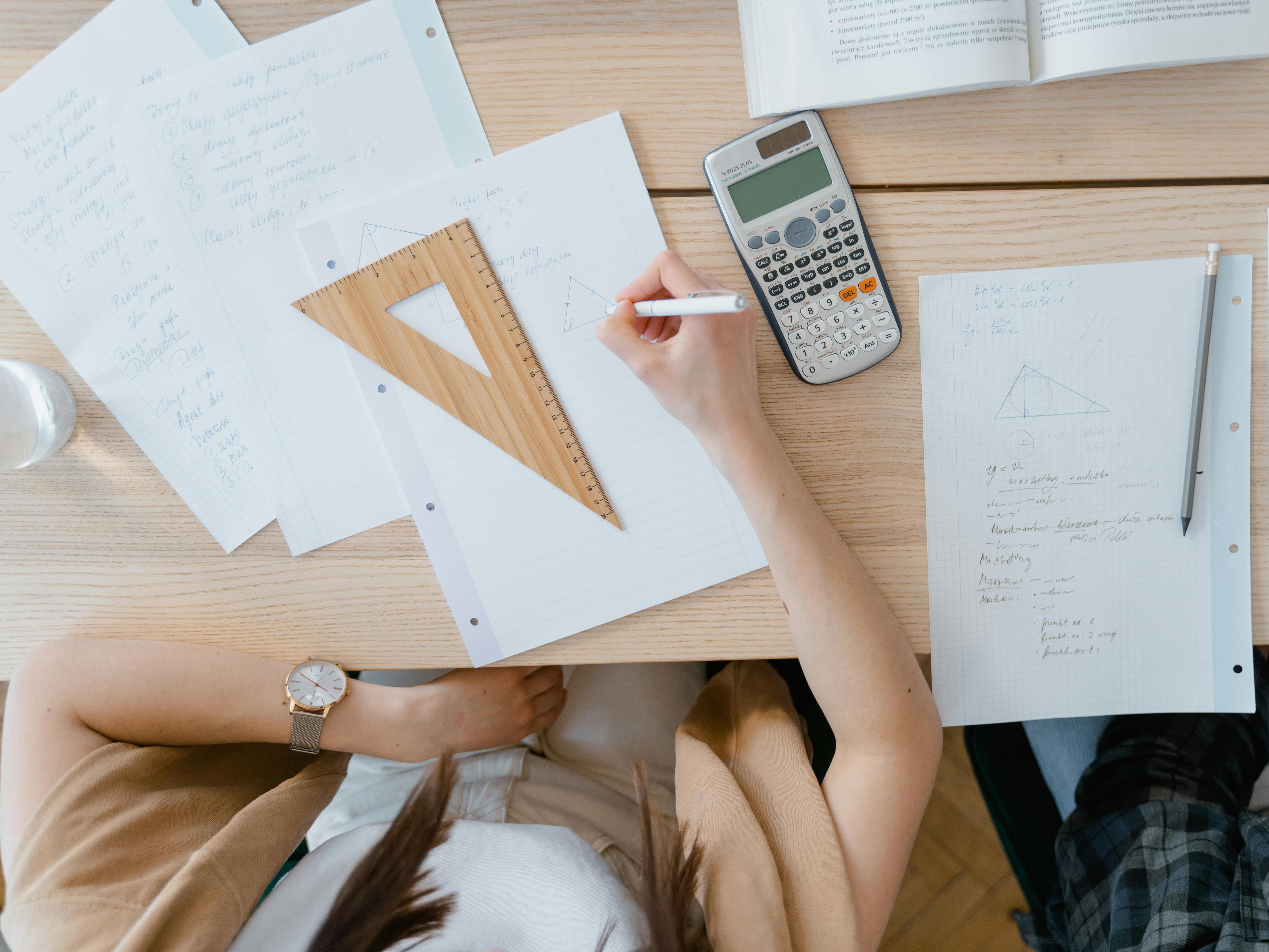 A student's works at a desk with papers and a calculator.