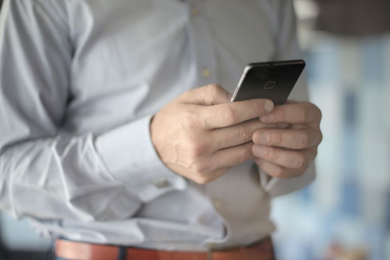 A person in a grey shirt using a cell phone.